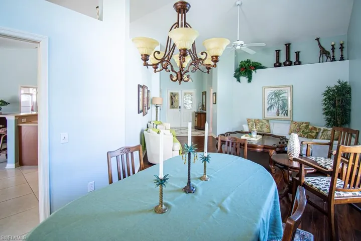 Dining area with light tile patterned floors and ceiling fan with notable chandelier