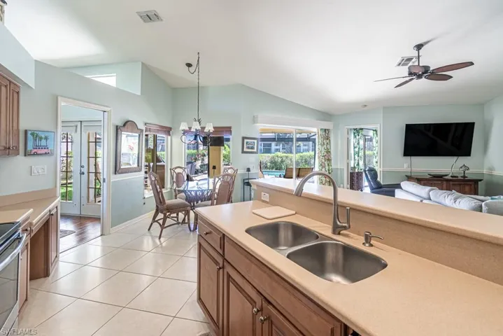 Kitchen featuring light tile patterned flooring, a sink, vaulted ceiling, and brown cabinets