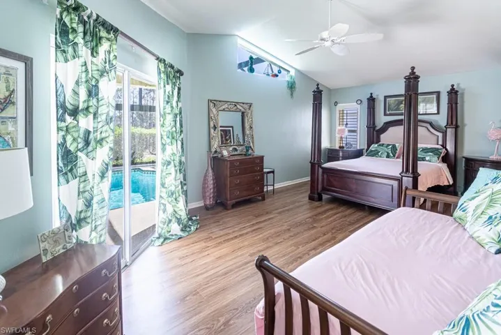 Bedroom with baseboards, lofted ceiling, access to exterior, and wood finished floors