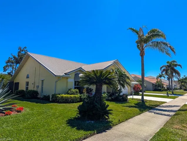 View of front facade featuring driveway, a garage, a front yard, a tile roof, and stucco siding