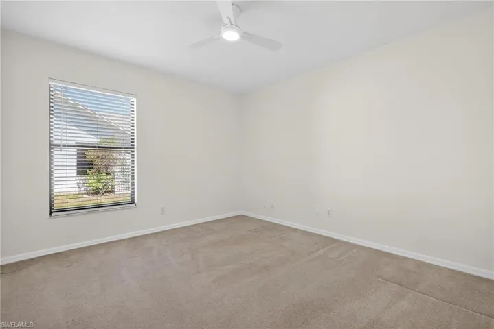 Carpeted empty room featuring baseboards and ceiling fan