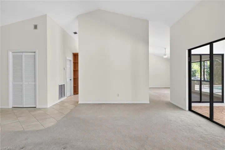 Spare room with lofted ceiling, light colored carpet, and light tile patterned flooring