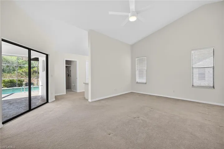 Unfurnished room with plenty of natural light, lofted ceiling, ceiling fan, and light colored carpet