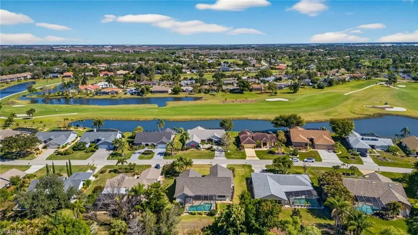 Aerial perspective of suburban area featuring a golf course and a nearby body of water