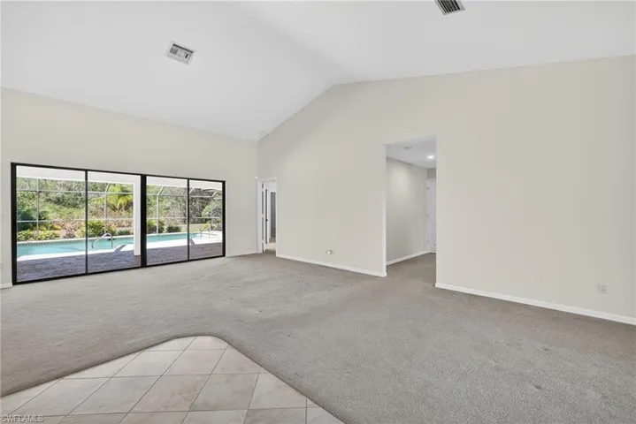 Unfurnished room with light colored carpet, a high ceiling, and light tile patterned floors