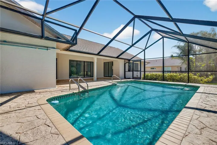 Swimming pool with a sunroom, a patio, and glass enclosure