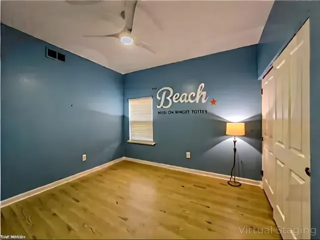 Unfurnished bedroom with visible vents, baseboards, ceiling fan, wood finished floors, and lofted ceiling