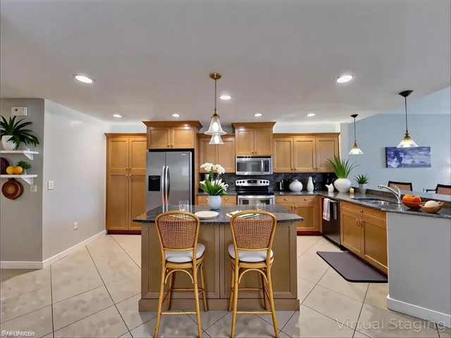 Kitchen featuring backsplash, light tile patterned flooring, stainless steel appliances, and a peninsula