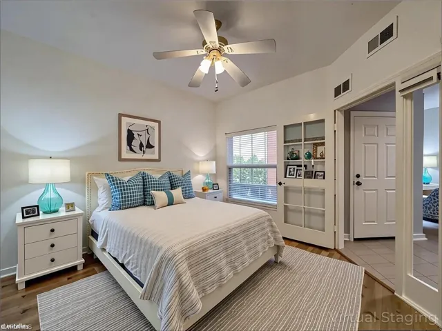 Bedroom with a ceiling fan, wood finished floors, and visible vents