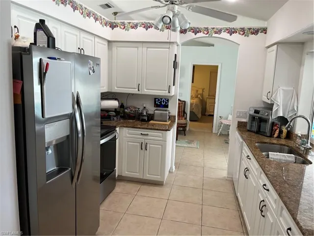 Kitchen with white cabinetry, sink, ceiling fan, and white refrigerator