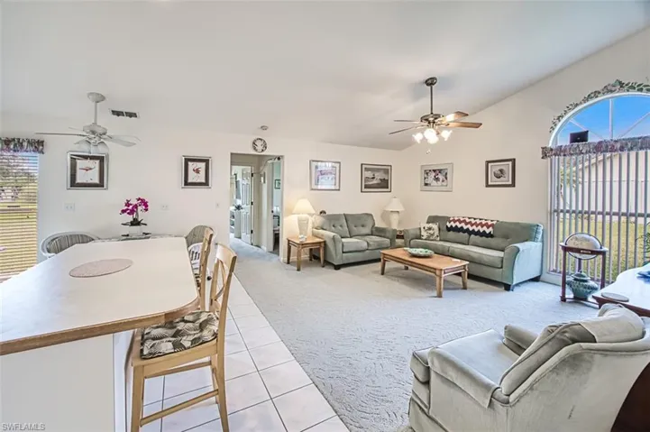 Kitchen in family room with ceiling fan, light colored carpet, and vaulted ceiling