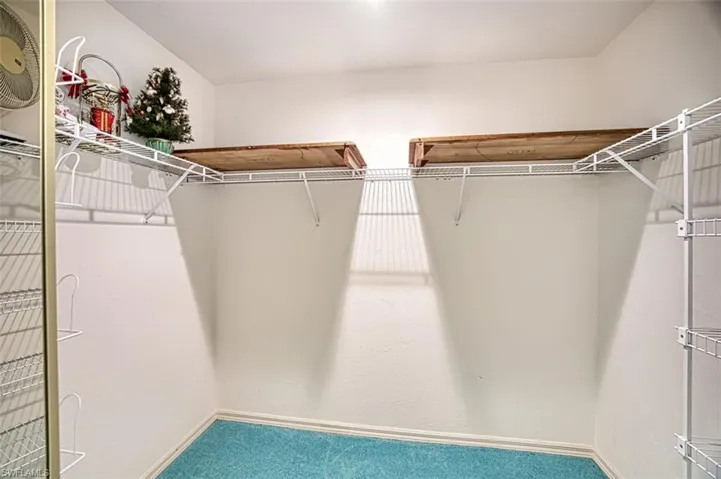 Well lit walk in closet with shelf storage