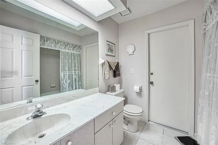 Bathroom with large vanity, white tile and shower over tub