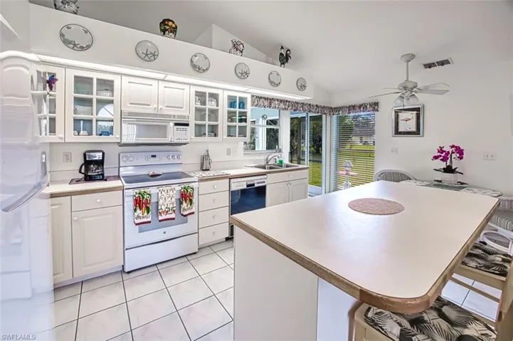 Kitchen with island, white cabinets with glass & white appliances