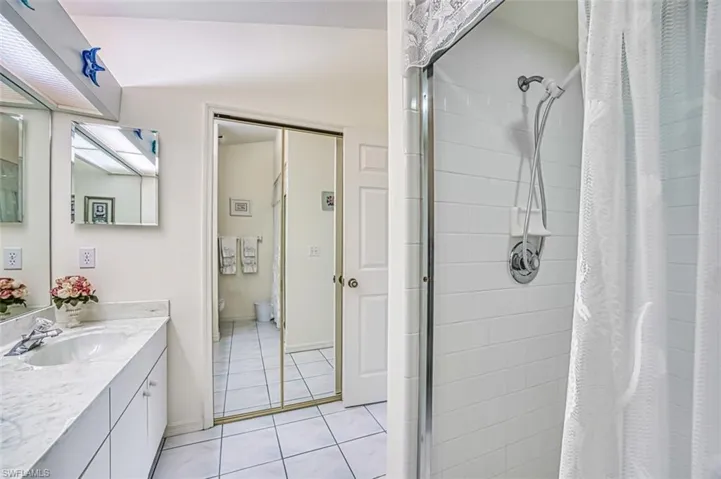 Bathroom with tile patterned floors, vanity, toilet, tile shower with glass door