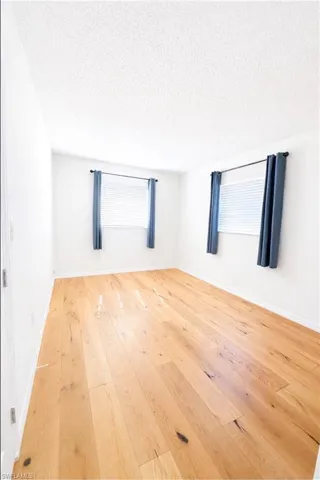Empty room featuring a textured ceiling and light wood finished floors