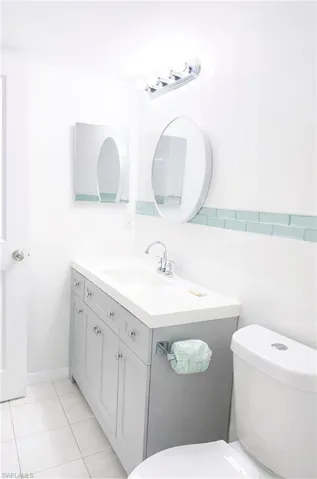 Half bath with vanity, tile walls, and light tile patterned floors