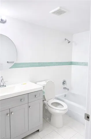 Full bathroom with tile walls, vanity, shower / bathtub combination, and light tile patterned floors