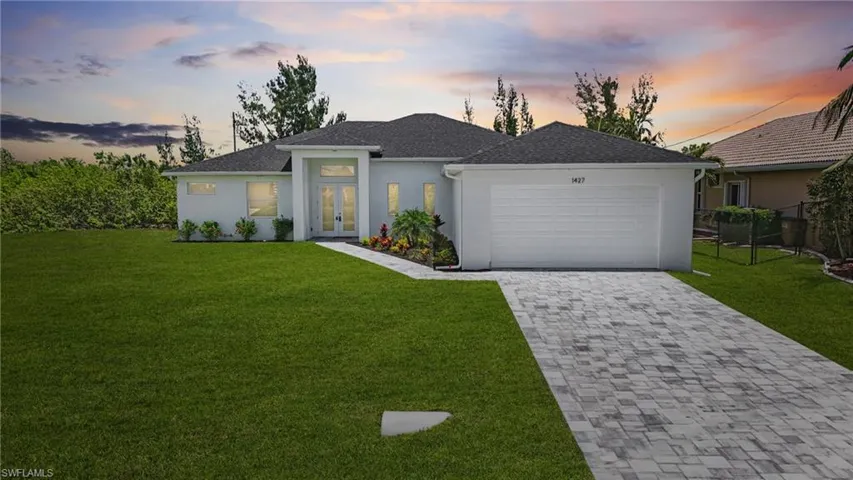 View of front of house with french doors, a garage, stucco siding, and decorative driveway