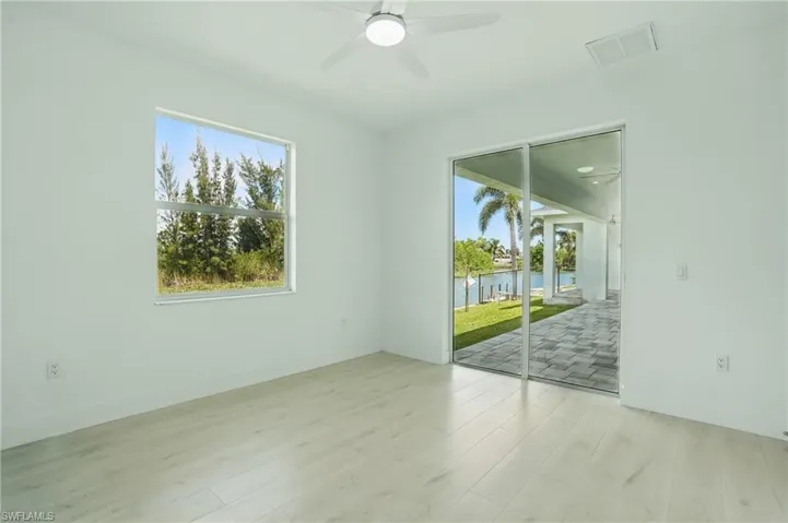 Empty room featuring plenty of natural light, wood finished floors, a water view, and ceiling fan
