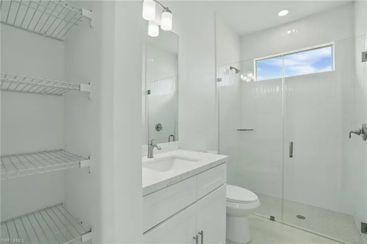 Full bathroom with toilet, a shower stall, vanity, and recessed lighting