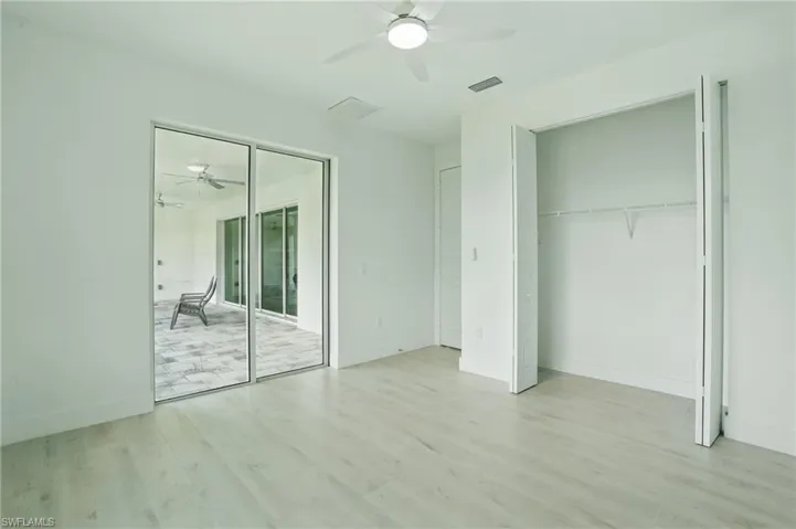 Unfurnished bedroom featuring light wood finished floors, ceiling fan, baseboards, and access to exterior