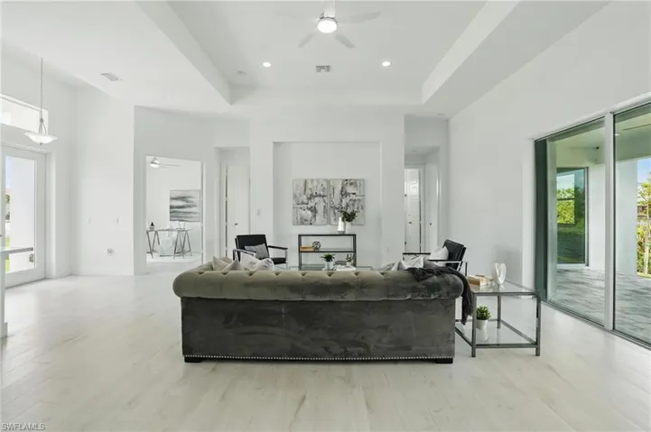 Living area featuring ceiling fan, light wood finished floors, and a tray ceiling