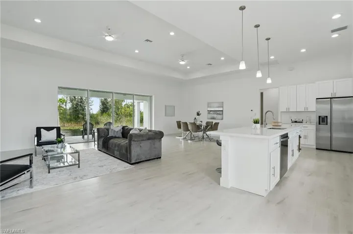 Kitchen with stainless steel appliances, a sink, a ceiling fan, open floor plan, and light countertops