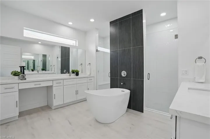 Bathroom featuring vanity, a shower stall, a freestanding bath, wood finished floors, and recessed lighting