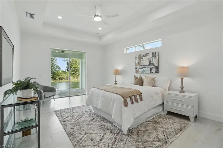 Bedroom with access to exterior, multiple windows, a raised ceiling, baseboards, and recessed lighting