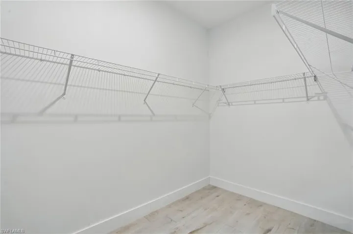 Walk in closet with light wood finished floors