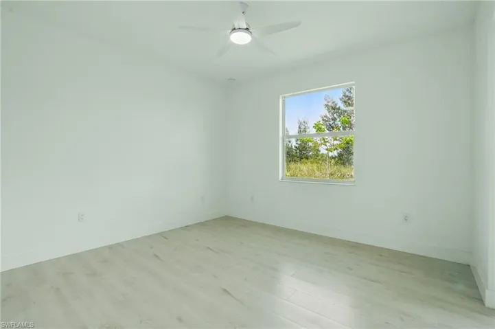 Spare room featuring light wood finished floors, baseboards, and ceiling fan