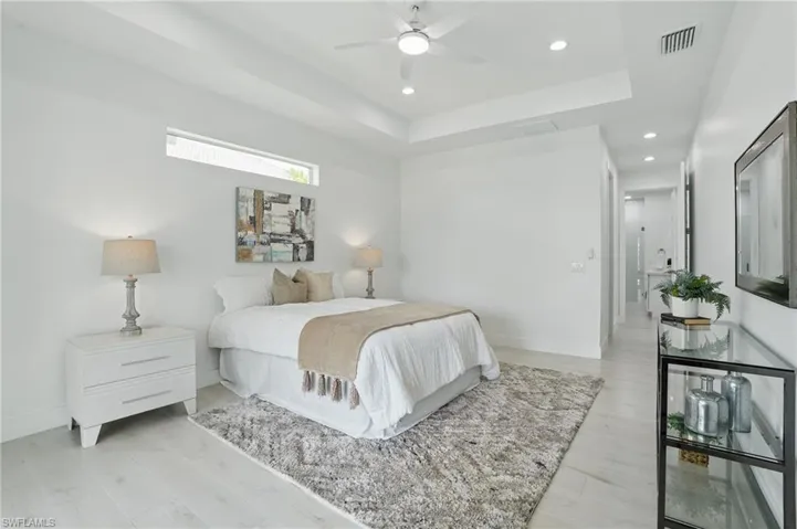 Bedroom with recessed lighting, baseboards, light wood finished floors, a tray ceiling, and a ceiling fan
