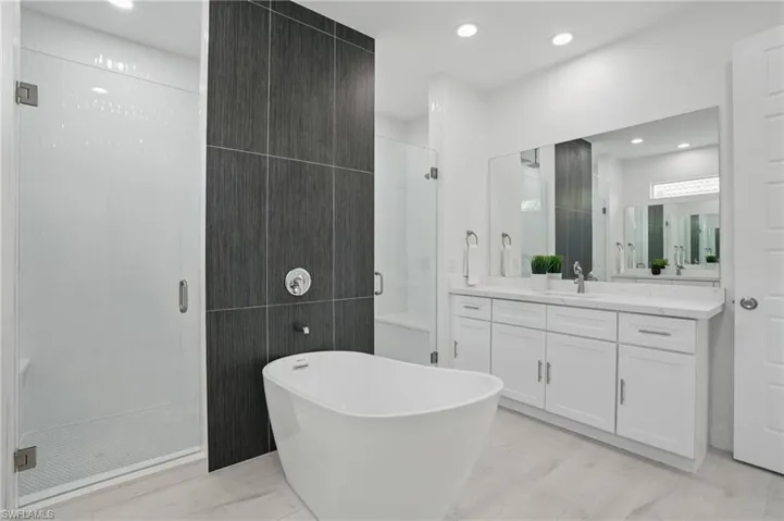 Bathroom with vanity, a stall shower, a freestanding bath, tile walls, and wood finished floors