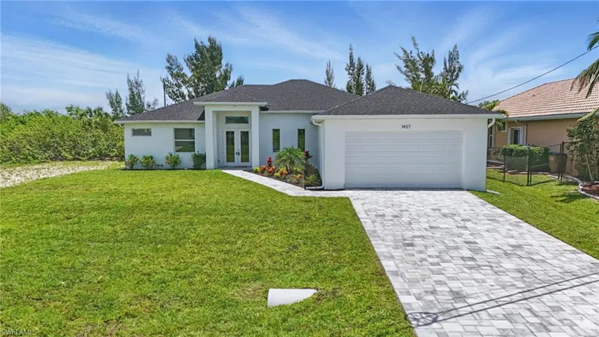 Prairie-style home with french doors, an attached garage, stucco siding, and decorative driveway