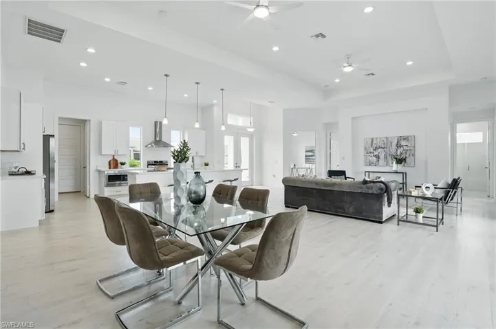 Dining room featuring a ceiling fan, light wood-style floors, recessed lighting, and a raised ceiling