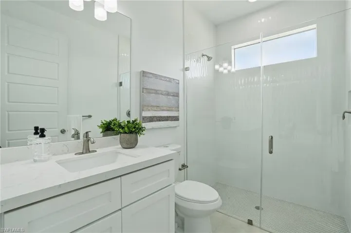 Bathroom featuring vanity, a shower stall, and toilet