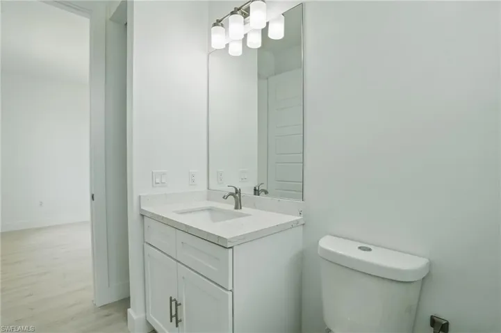 Half bath with vanity, toilet, and wood finished floors