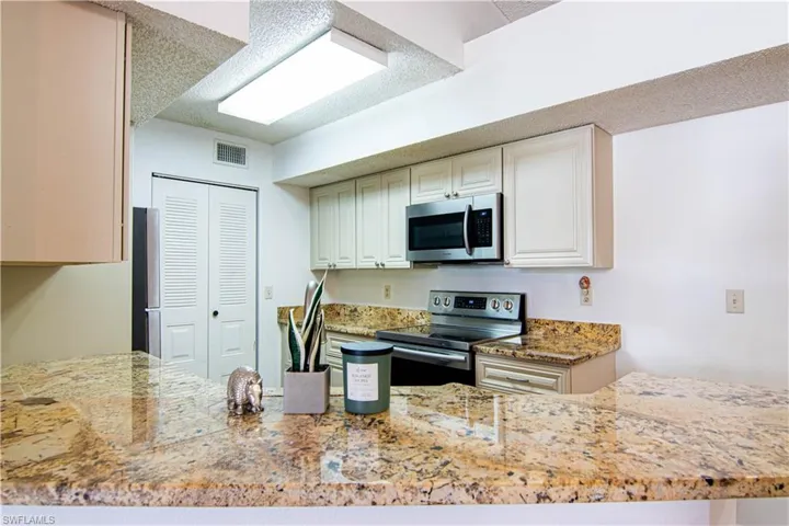Kitchen featuring appliances with stainless steel finishes and light stone counters