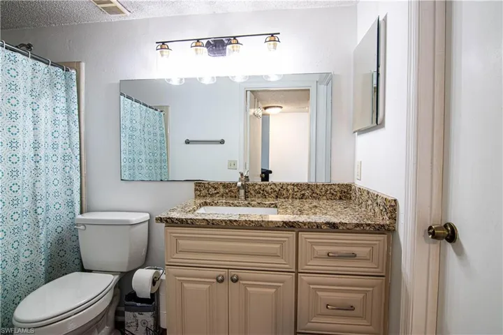 Bathroom featuring a textured ceiling, a shower with shower curtain, and vanity