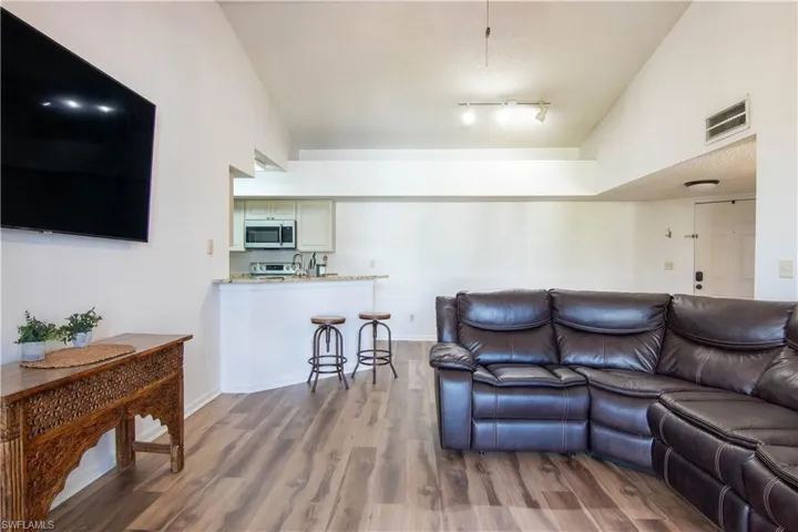 Living room featuring lofted ceiling, dark wood finished floors, and a textured ceiling