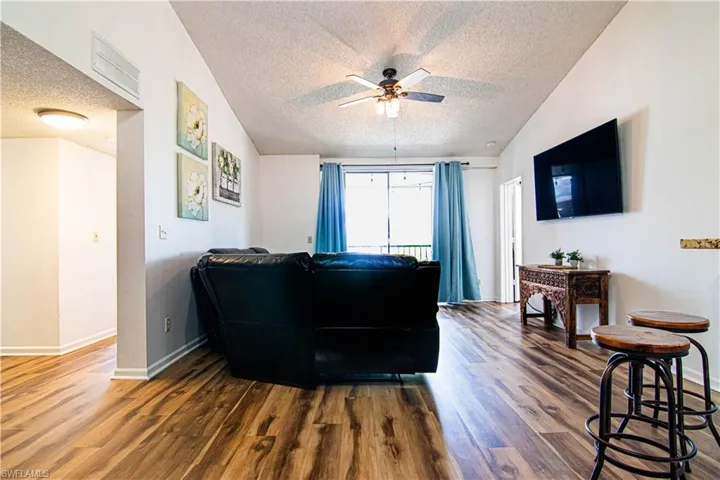 Living area featuring a textured ceiling, wood finished floors, and a ceiling fan
