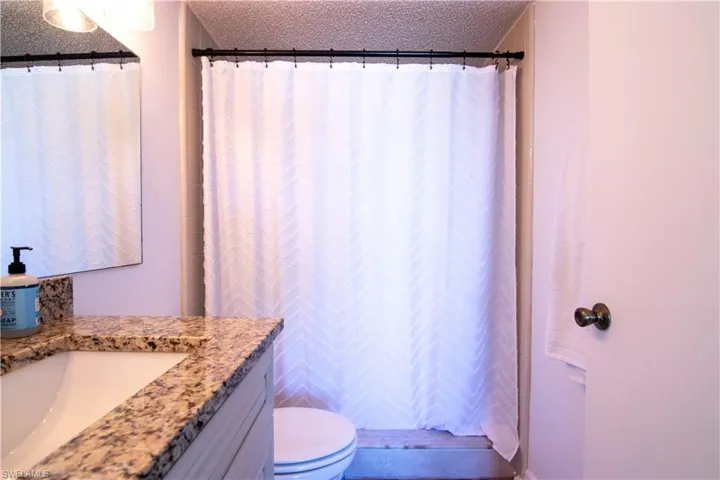 Full bathroom with a shower with curtain, a textured ceiling, and vanity