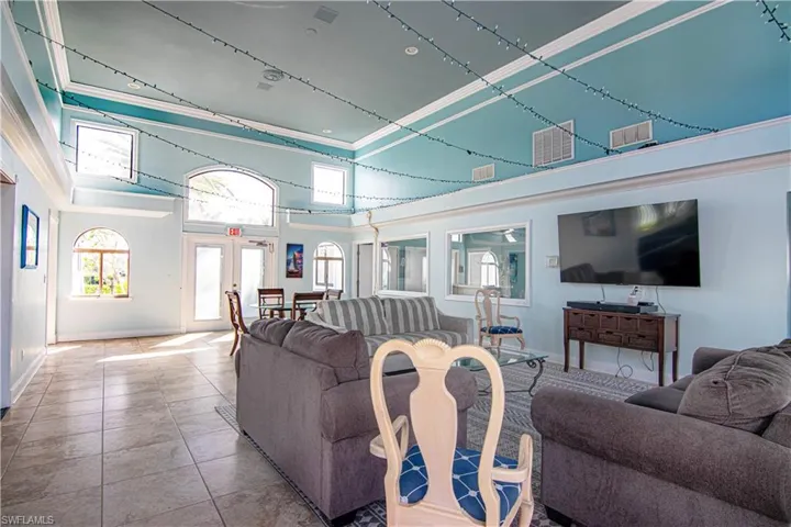 Tiled living area with french doors, a high ceiling, and ornamental molding