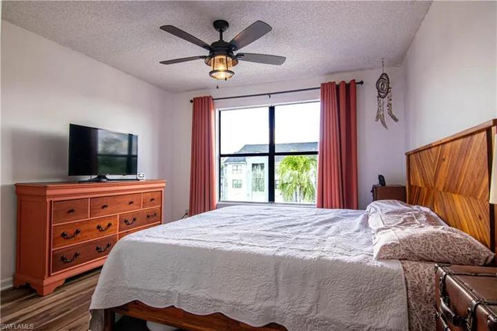 Bedroom with a textured ceiling, wood finished floors, and a ceiling fan