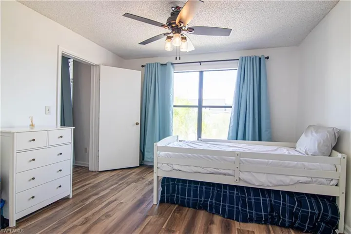 Bedroom with dark wood-type flooring, a textured ceiling, and a ceiling fan