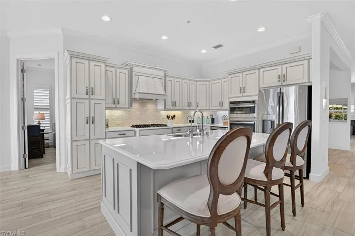 Kitchen featuring stainless steel appliances, glass backsplash, a breakfast bar area, at kitchen island, with easy entry to Den