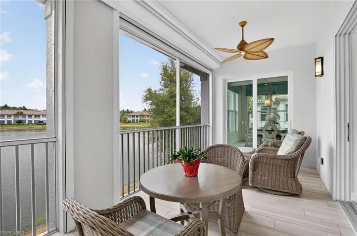 Lanai featuring ceiling fan, a balcony, and a water view. Same wood look upgraded plank tile flooring to match the entire interior of residence. Beautiful setting for all to enjoy.