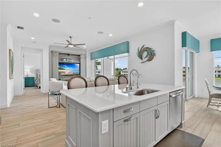 Kitchen with a center breakfast bar island with sink, recessed lighting, light wood finished floors, and crown molding
