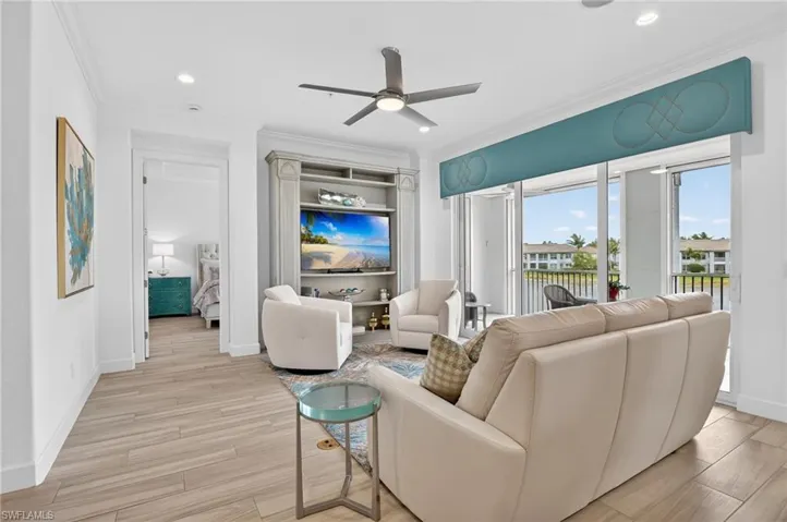 Living room with custom shelving, ceiling fan, and a water view